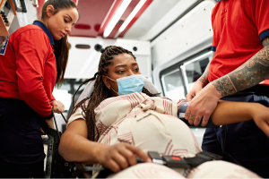 A pregnant person is transferred in an ambulance to the hospital for care.