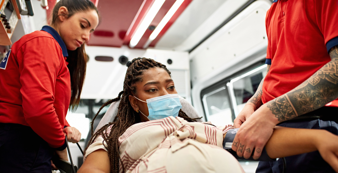 A pregnant person is transferred into an ambulance for care.