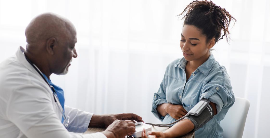 A doctor measures a pregnant person's blood pressure.